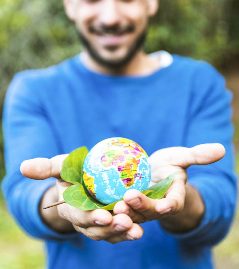 male-holding-globe-with-green-leaf-and-smiling (1)